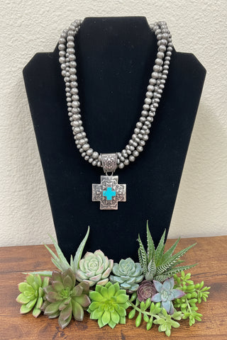 Triple strand silver toned pearl necklace with faux turquoise cross pendant and matching earrings