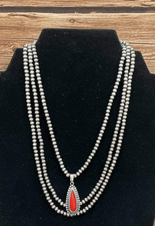 Red faux stone layered necklace with triple strands of silver toned pearls and teardrop pendant