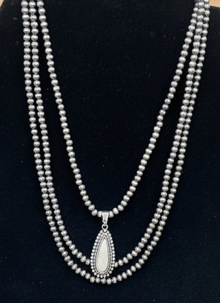 White faux stone layered necklace with triple strands of silver toned pearls and teardrop pendant